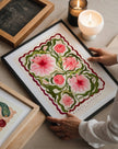 Framed floral artwork on a table with candles and a chalkboard in the background