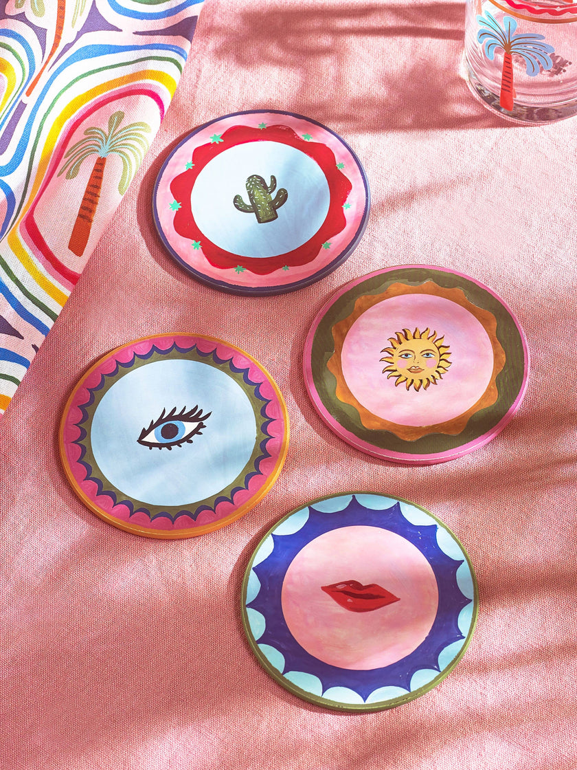 Set of colorful coasters with artistic designs on a pink surface