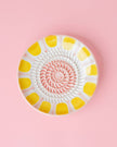 Decorative plate with yellow and white pattern on a pink background