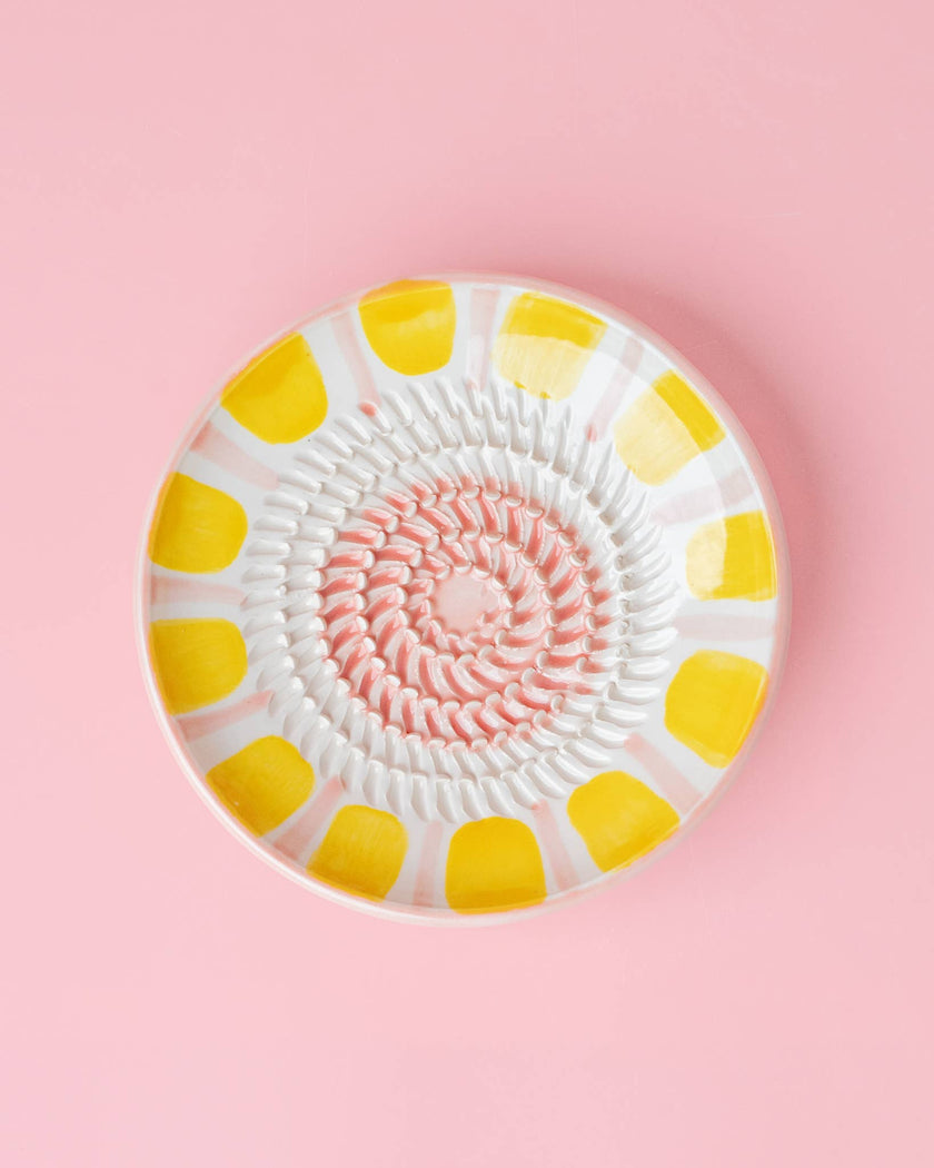Decorative plate with yellow and white pattern on a pink background