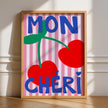 Framed artwork with 'MON CHERI' text and cherries on a striped background