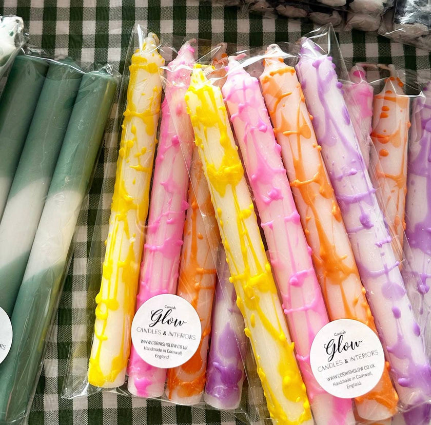 Colorful candles in packaging with 'Glow' label on a checkered background
