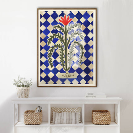 Framed artwork with a floral design on a blue and white checkered background, displayed on a wall above a white shelf.