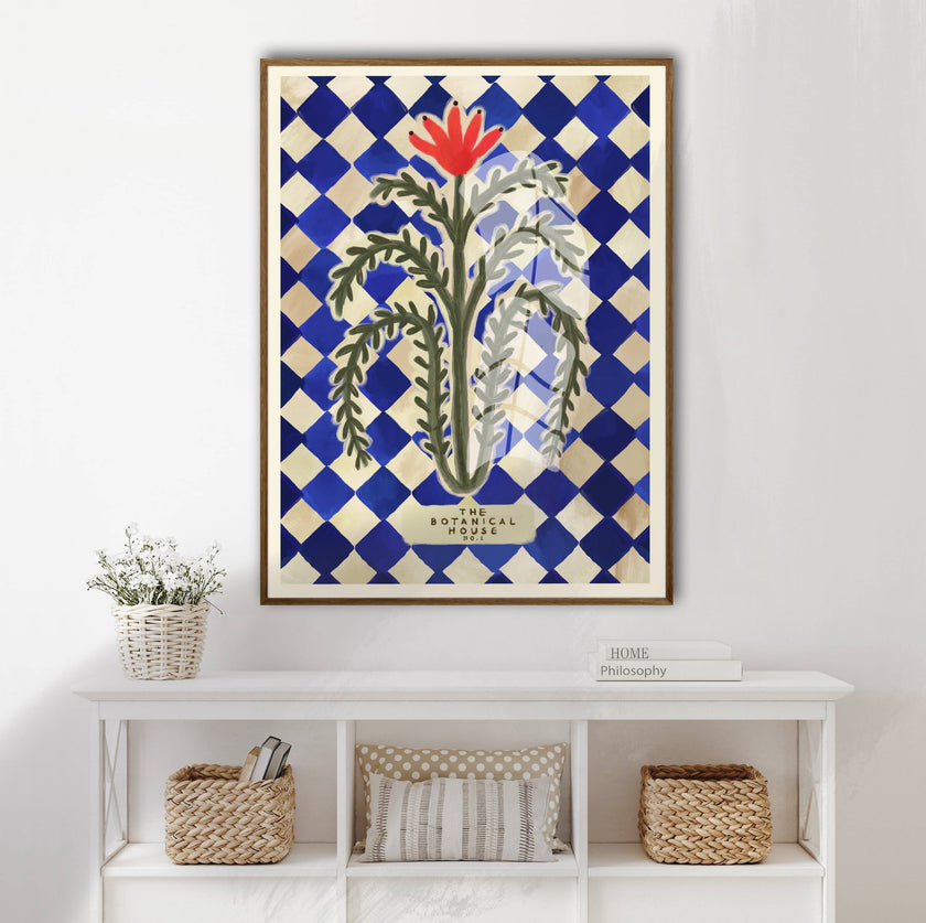 Framed artwork with a floral design on a blue and white checkered background, displayed on a wall above a white shelf.