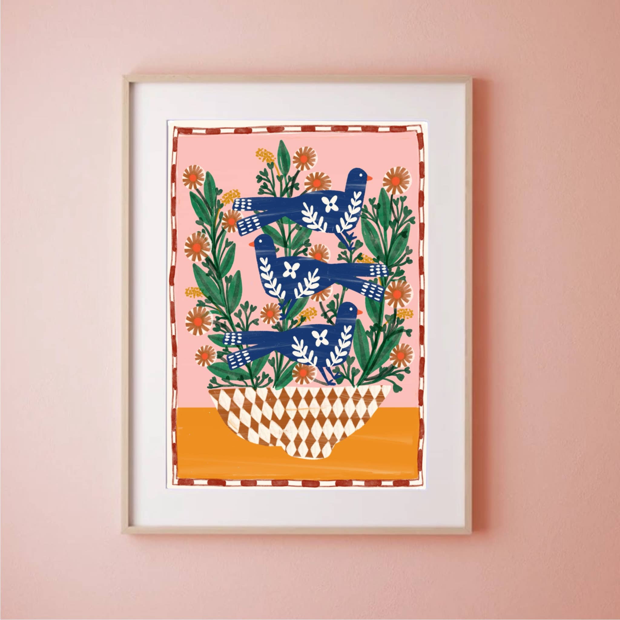 Framed artwork with blue birds and green leaves on a pink wall