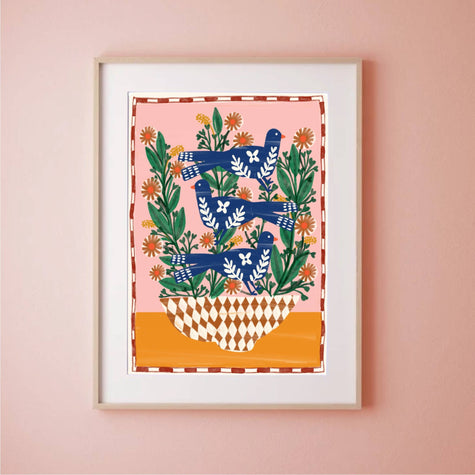 Framed artwork with blue birds and green leaves on a pink wall