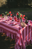 Decorated outdoor table with red and white striped tablecloth, flowers, and cutlery.