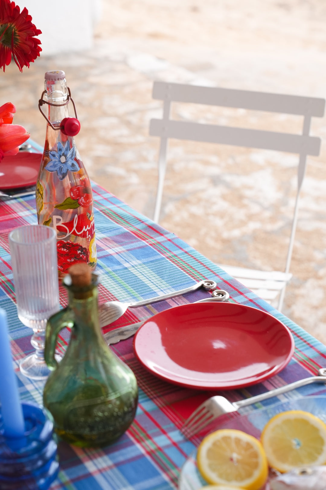 Table setting with plaid tablecloth, bread, and wine glasses outdoors.