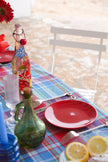 Table setting with plaid tablecloth, bread, and wine glasses outdoors.