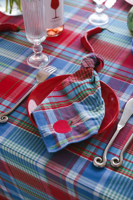 Table setting with red plate, blue plaid tablecloth, and decorative napkin.