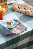 Plaid tablecloth with cutlery and a napkin on a table setting.