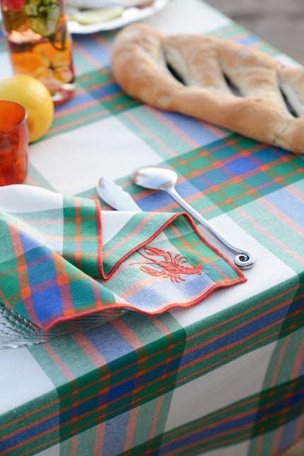 Plaid tablecloth with cutlery and a napkin on a table setting.
