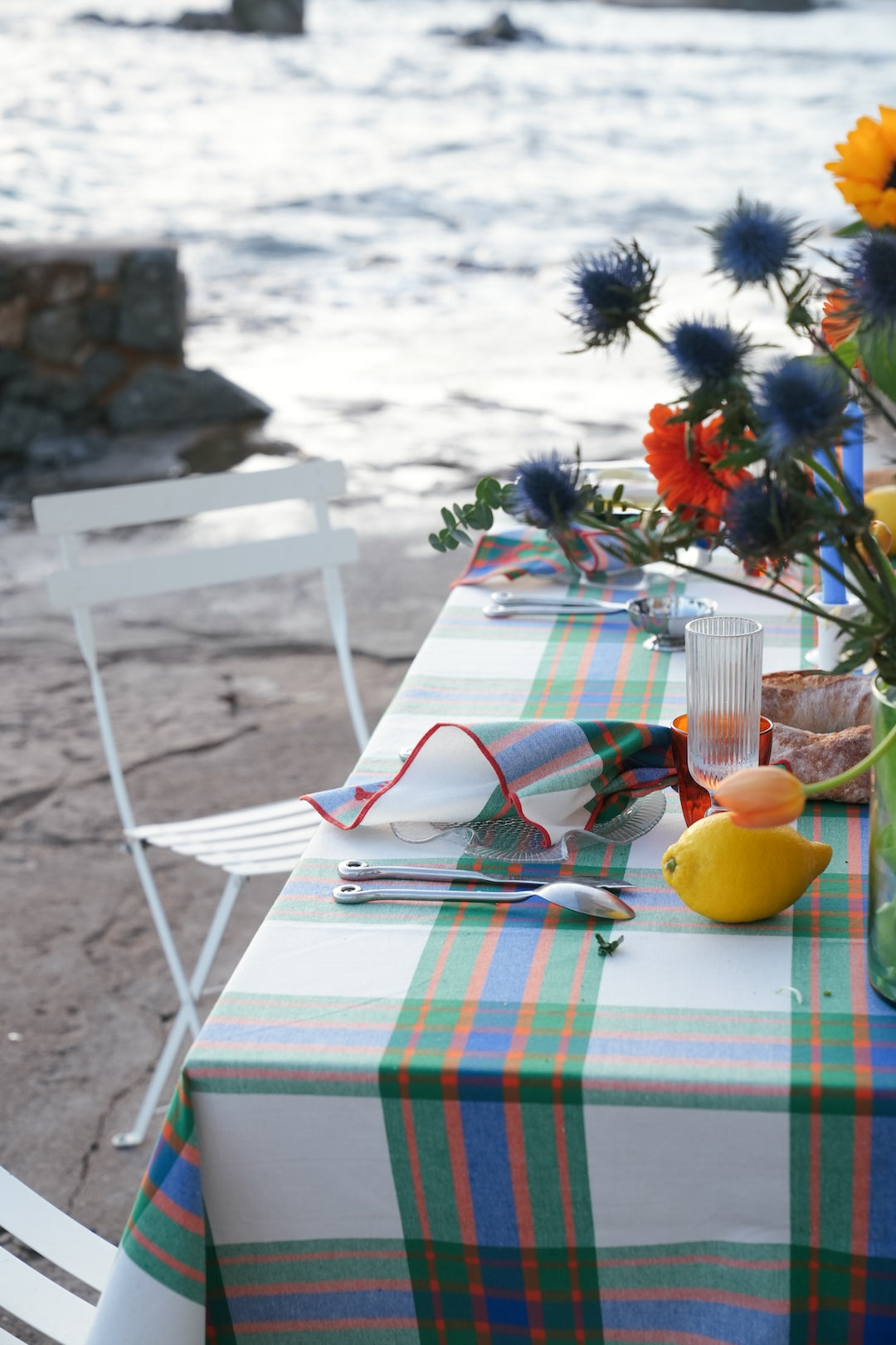 Colourful plaid tablecloth  on a dining table with flowers by the sea.