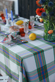 Dining table with flowers , lemons and candles with a check tablecloth in green, blue and orange.