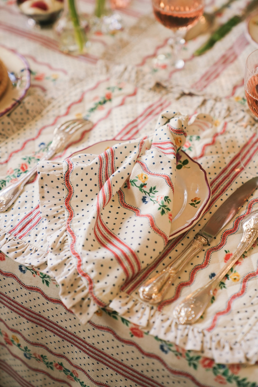 Decorative napkin with floral and polka dot patterns on a tablecloth with floral designs.