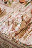 Decorative napkin with floral and polka dot patterns on a tablecloth with floral designs.