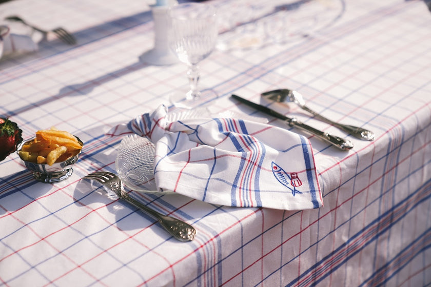 Table setting with cutlery, napkin, and fruit on a checkered tablecloth.