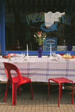 Red chairs and table with a checkered tablecloth in front of a window with 'Fish Tank' branding.