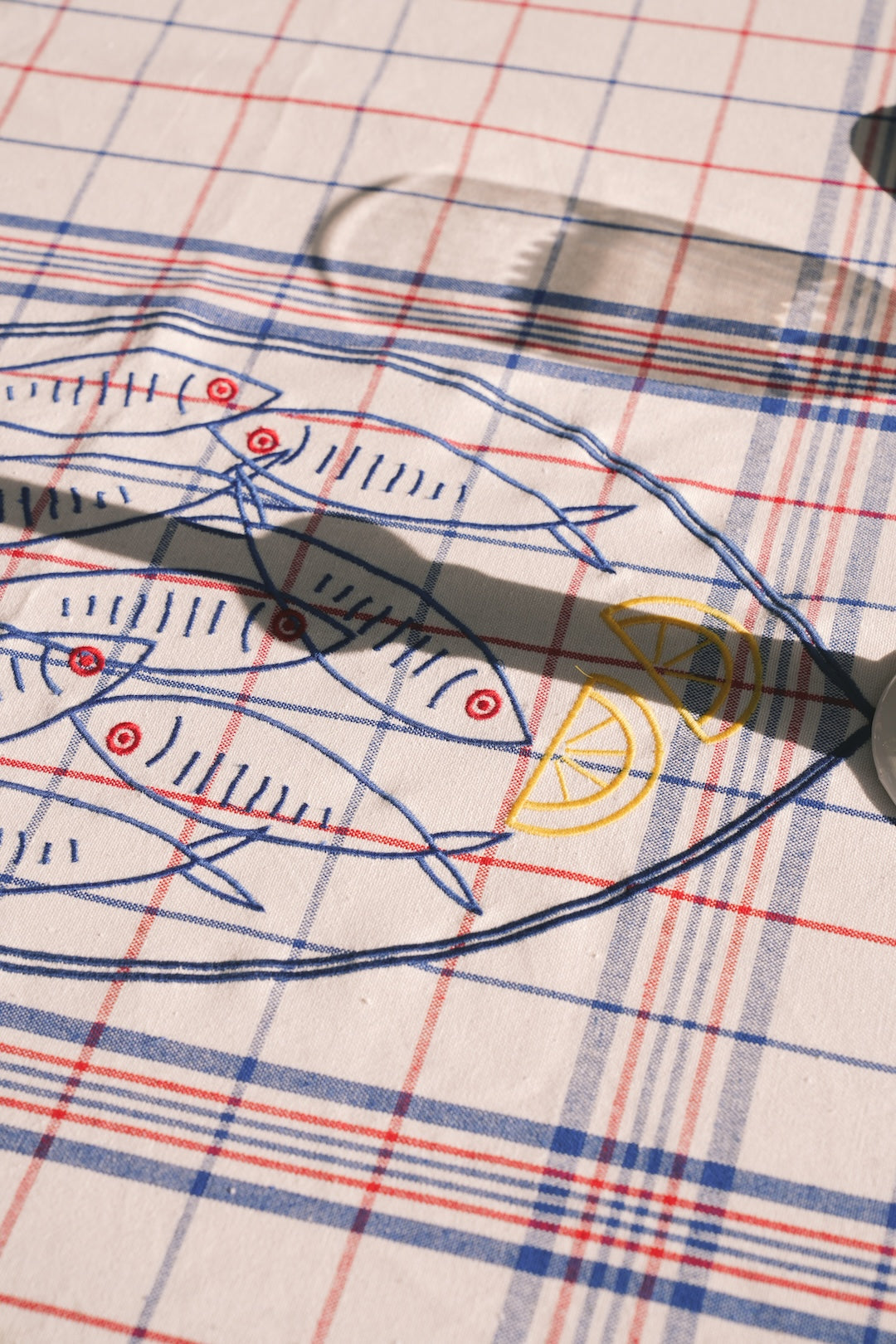 Fish-themed embroidery on a red, blue and white checkered tablecloth 