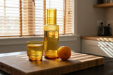 Amber glass bottles and glass with an orange on a bright kitchen