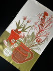 Decorative tea towel with bird, floral and pot design on a white background