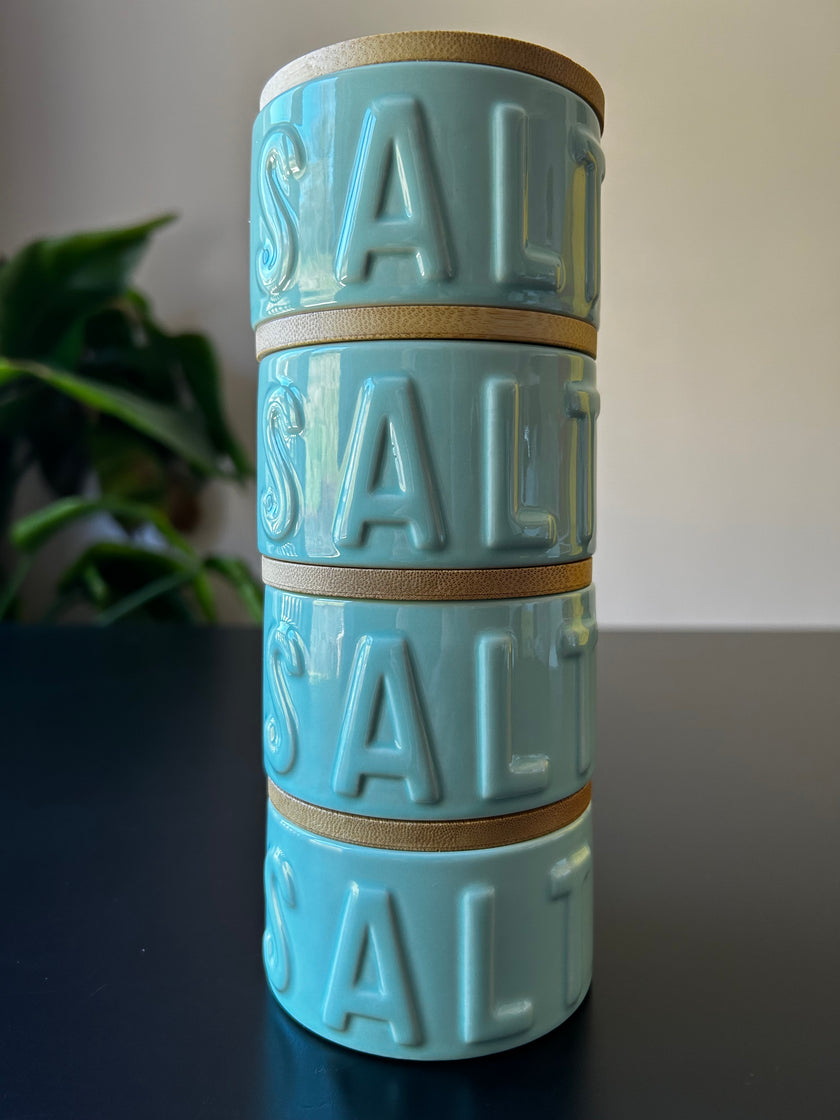 Stack of four mint green salt pots embossed with the word 'Salt' on a white background