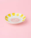 Decorative plate with yellow and white pattern on a pink background