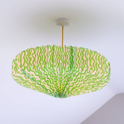 Ceiling lightshade with a green and pink patterned shade against a white wall.