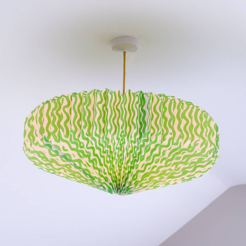 Ceiling lightshade with a green and pink patterned shade against a white wall.