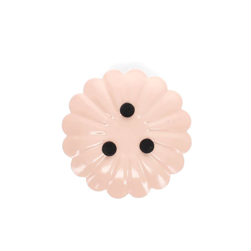 Pink flower-shaped object with black centers on a white background