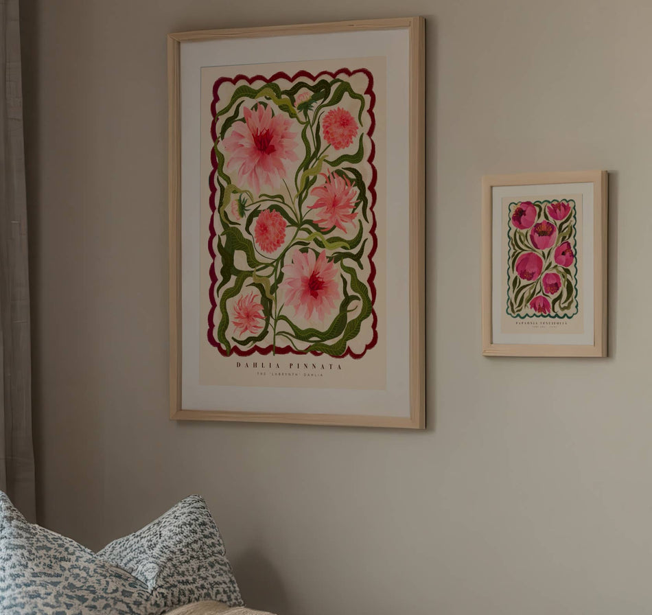 Framed floral artwork on a wall with a pillow in the foreground.