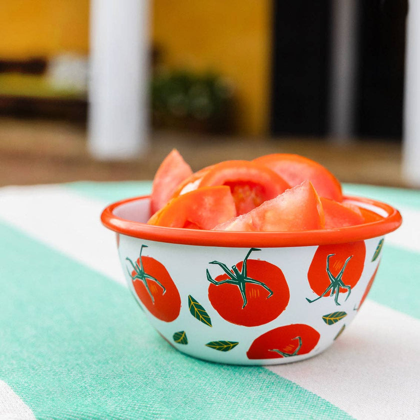 Small bowl with tomato pattern filled with sliced tomatoes on a green surface.