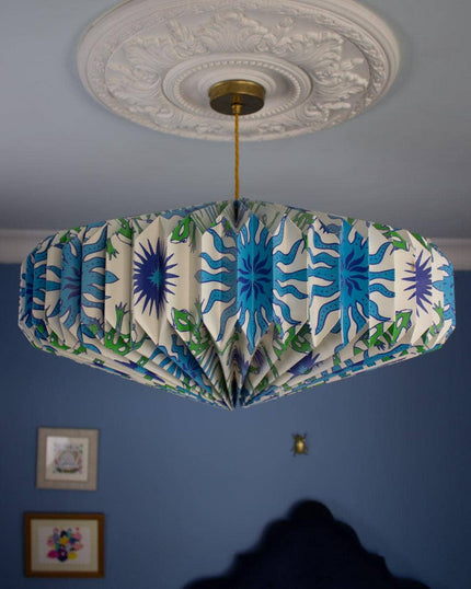 Blue and green ceiling lightshade with a colourful pattern on a blue wall.