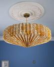 Decorative paper ceiling lightshade with floral yellow pattern against a blue wall.