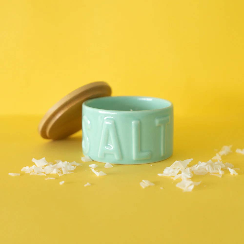 Green salt container with wooden lid on a yellow background