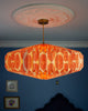 Decorative ceiling paper lightshade with orange patterned shade against a blue wall.