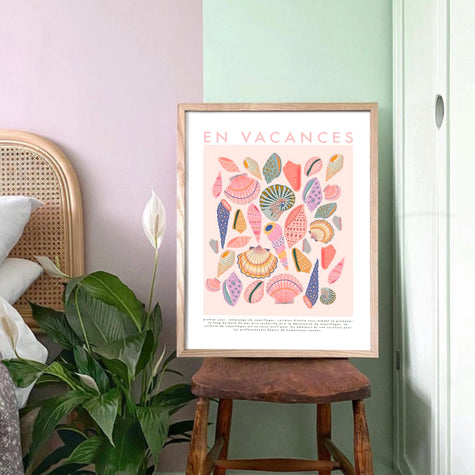Framed artwork with floral design and text on a wall next to a plant and chair.
